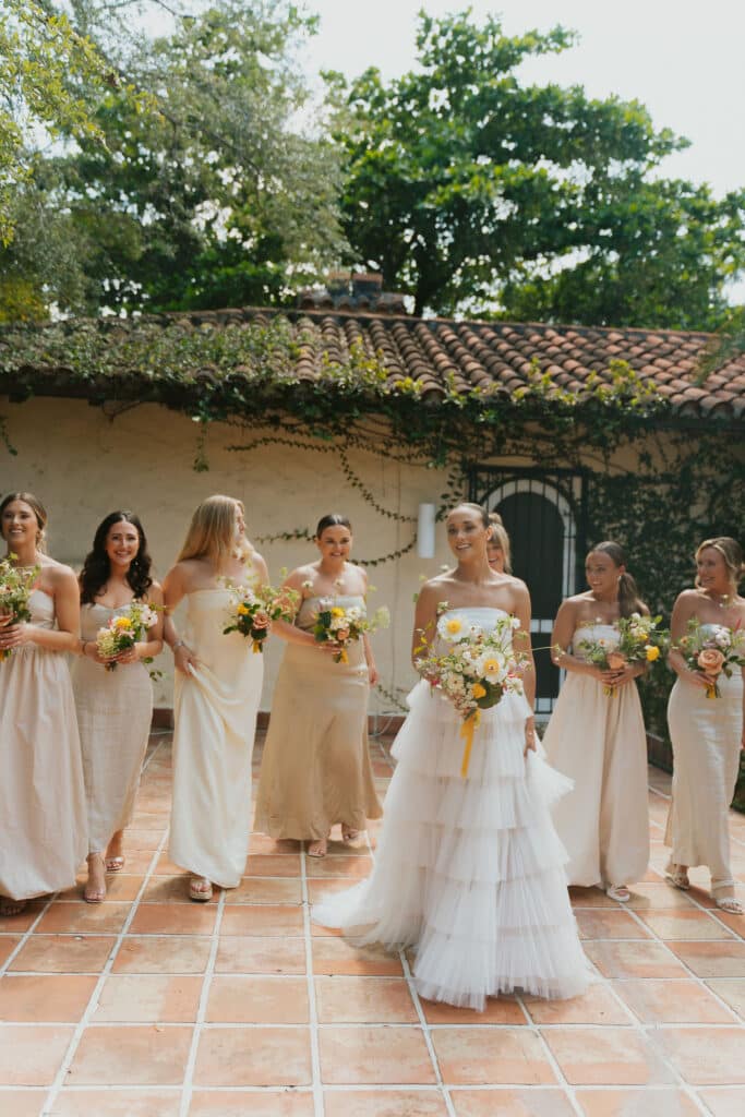 bridal party that is chic walking with their bride bouquets