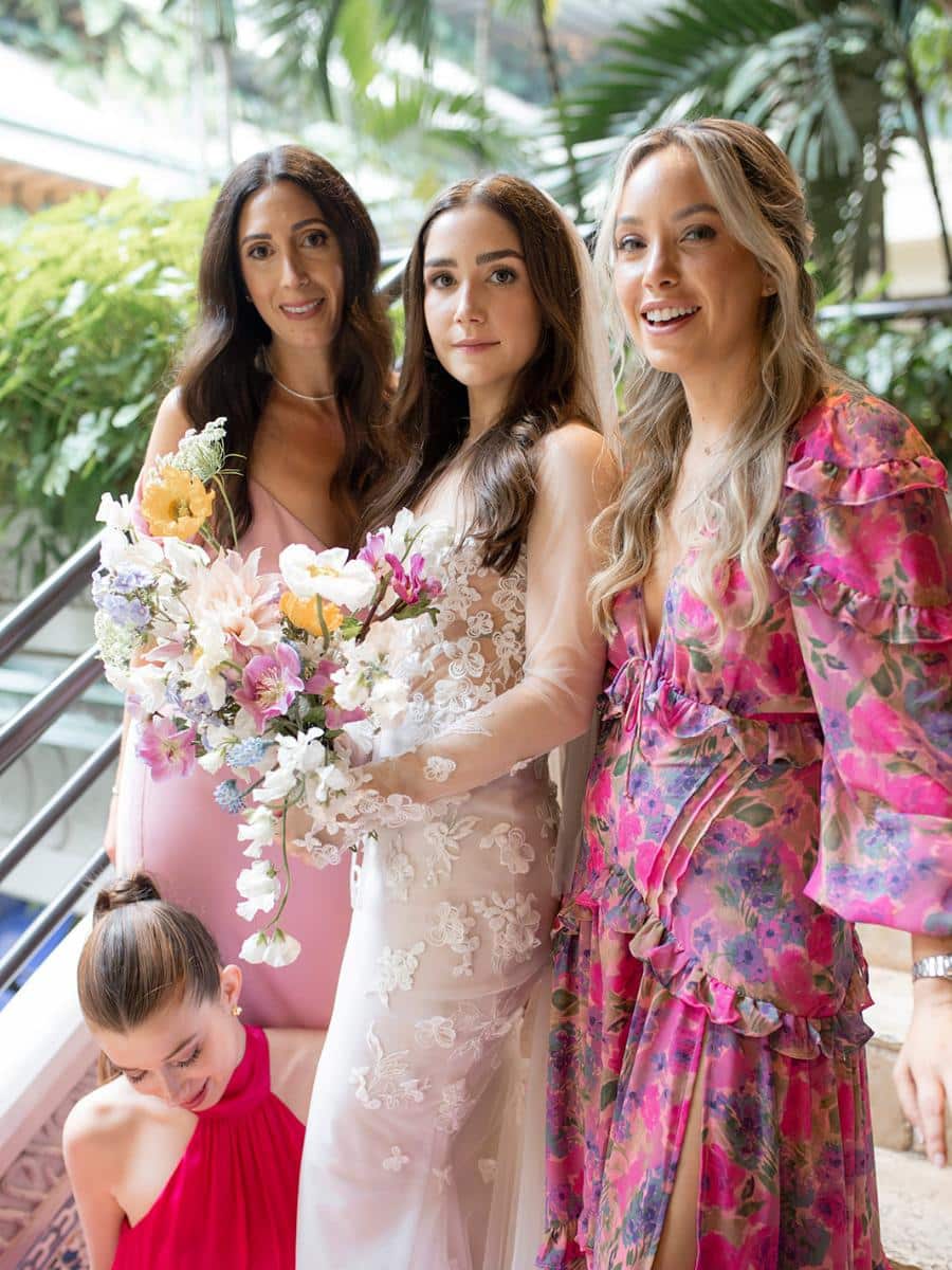 bride with bridesmaids in pastel dresses holding a bouquet at a mayfair wedding