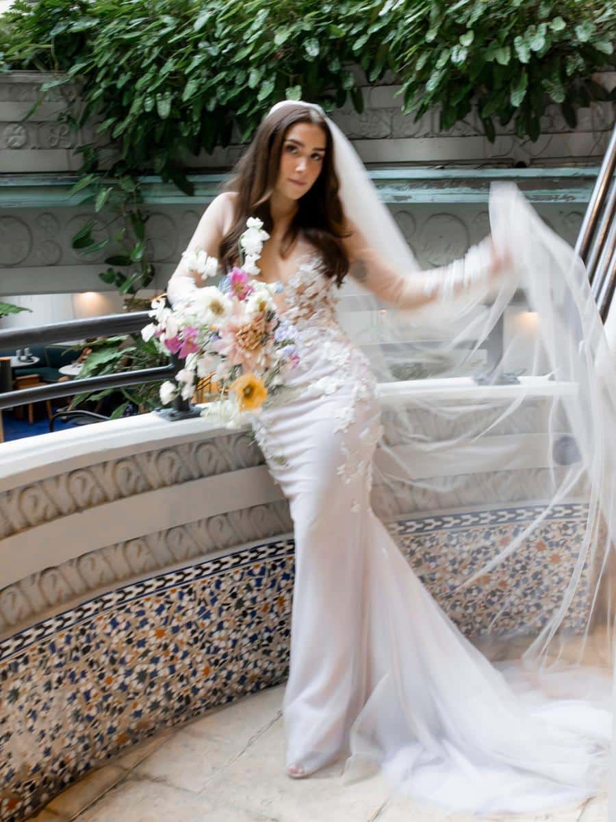 bride in stunning embroidered gown holding a whimsical wildflower bouquet