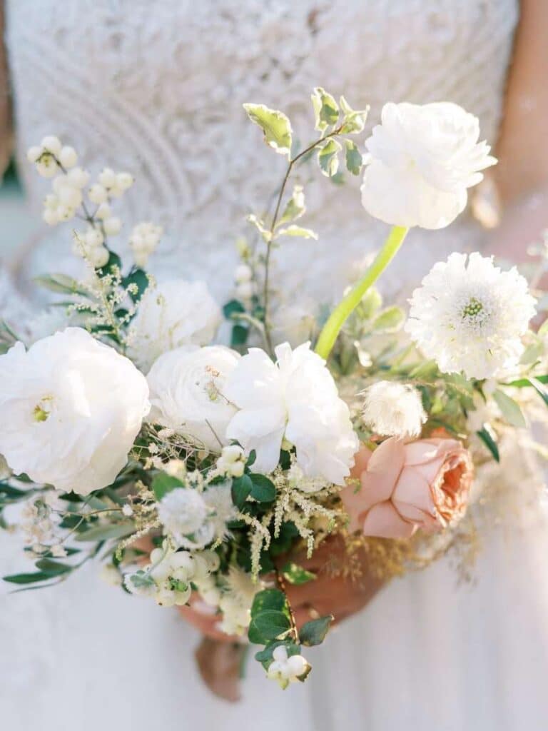 close-up of bride's hand holding a delicate white and pink floral wedding bouquet