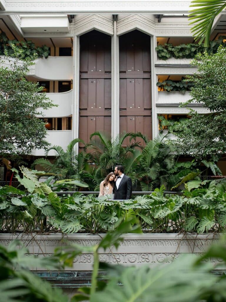 bride and groom sharing a moment on balcony amid dense foliage at coconut grove wedding