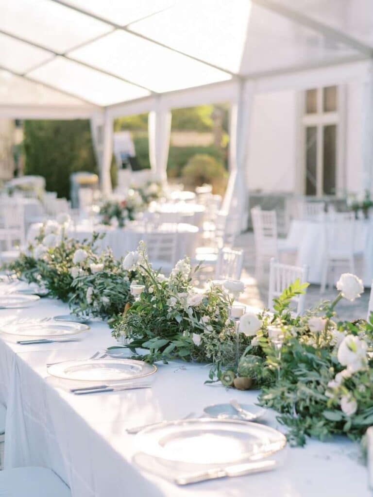 elegant outdoor wedding reception setup with white flowers and linens under a tent