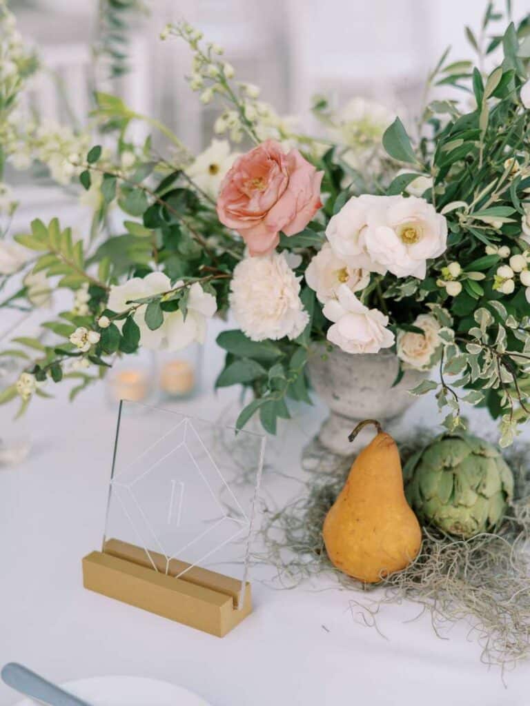 elegant wedding centerpiece with white flowers and pear on table at vizcaya garden