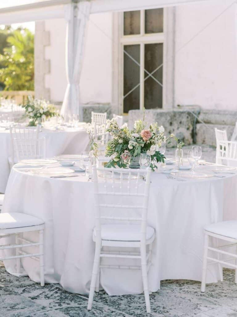 romantic white wedding reception table settings with floral centerpieces at vizcaya garden